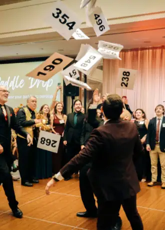 People celebrating and throwing numbered papers at Camp One Step event.