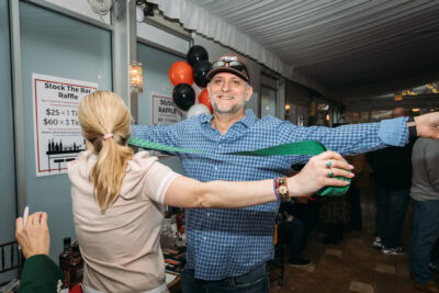 Joyful man and woman at Camp One Step fundraiser event, smiling with wide arms open.