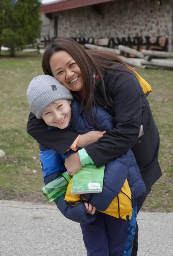 Joyful mother hugging her smiling son outdoors at Camp One Step.