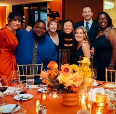 Beautiful diverse group celebrating at Camp One Step charity event with vibrant decor and joyful atmosphere.