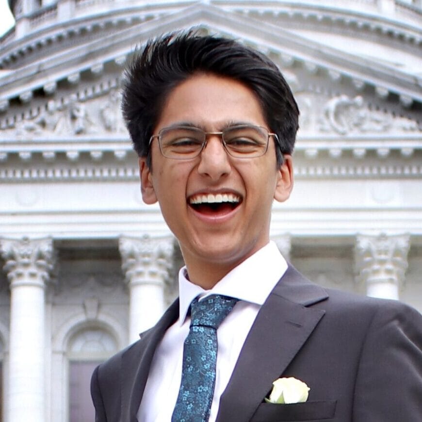 Joyful man in suit smiling outside government building for Camp One Step event.