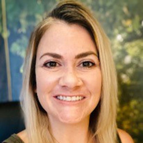 Smiling woman at Camp One Step outdoor setting, fostering hope for children with cancer.