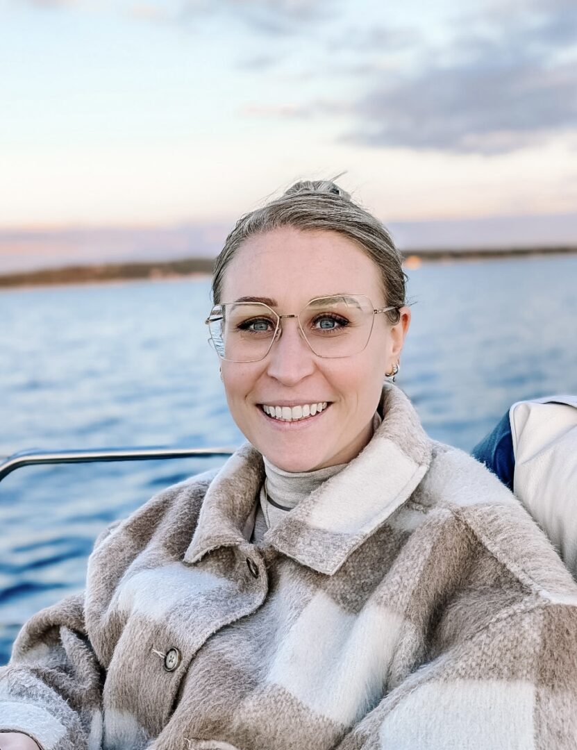 Smiling woman in glasses aboard a boat at sunset