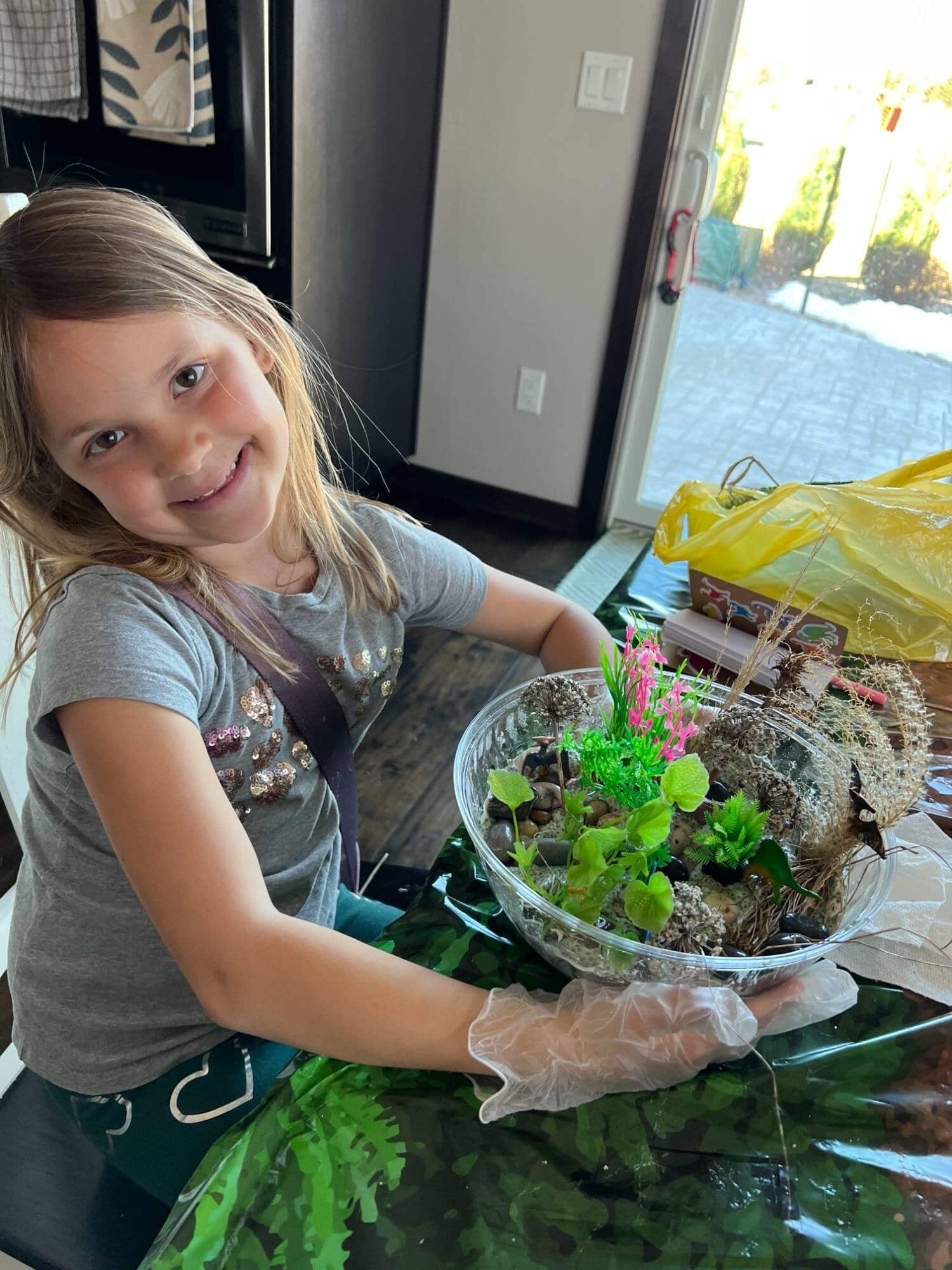 Child making a DIY fairy garden with plants and natural elements.