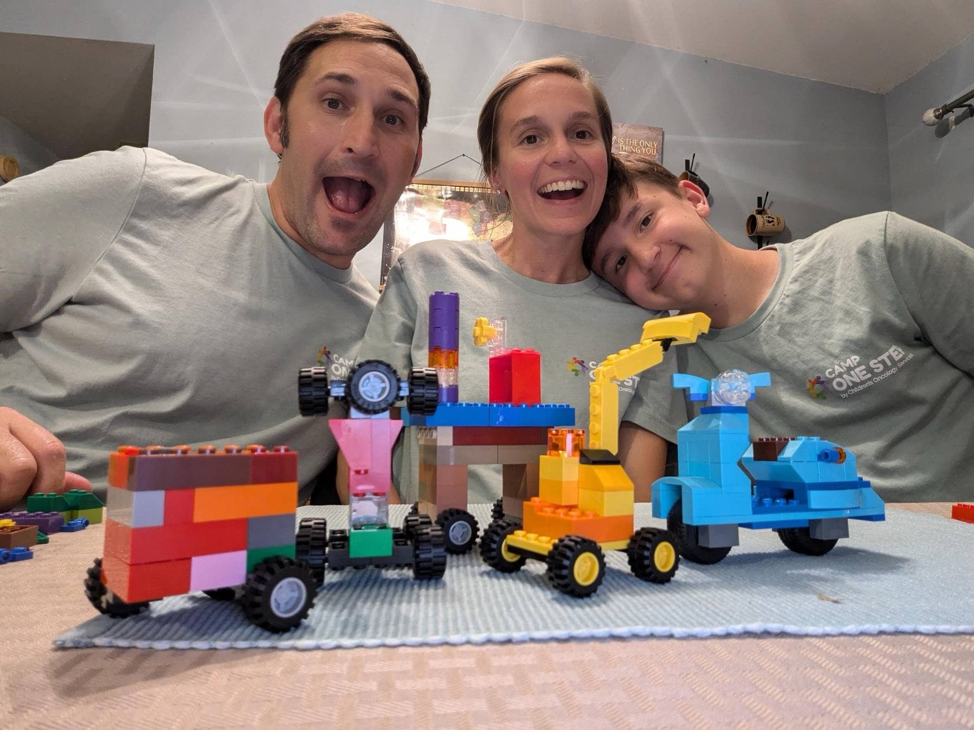 Family happily building LEGO creations at Camp One Step. Engaging activities for children with cancer, fostering joy and connection.