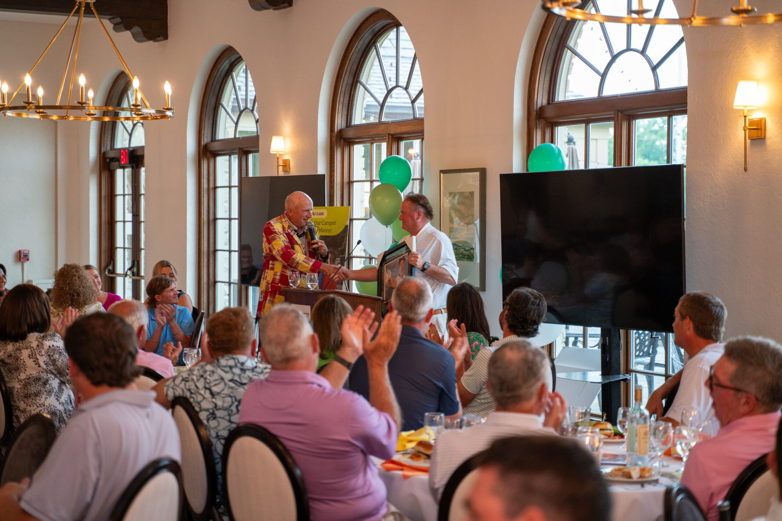 Man presenting framed award at banquet event