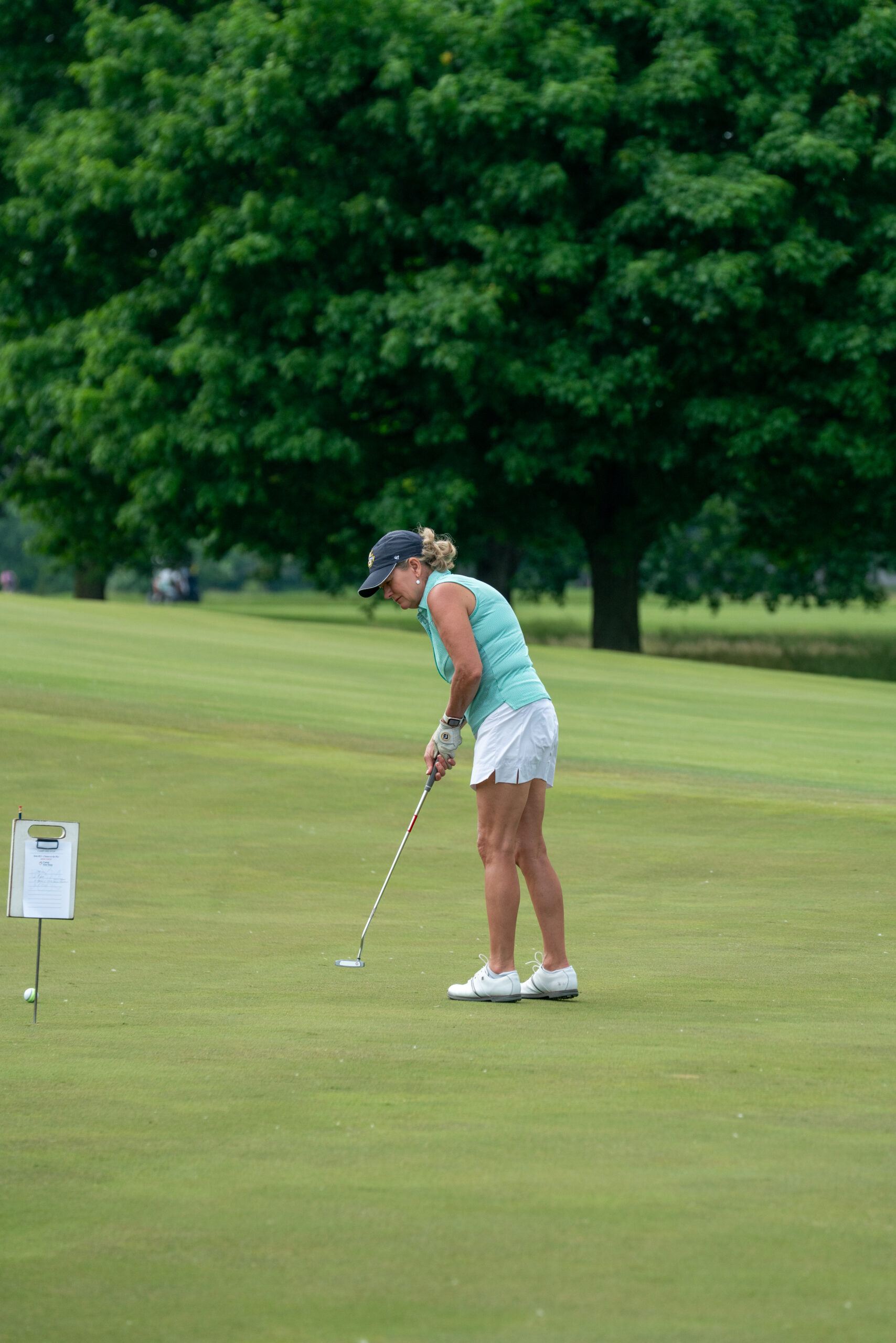 Woman golfer putting on a green course