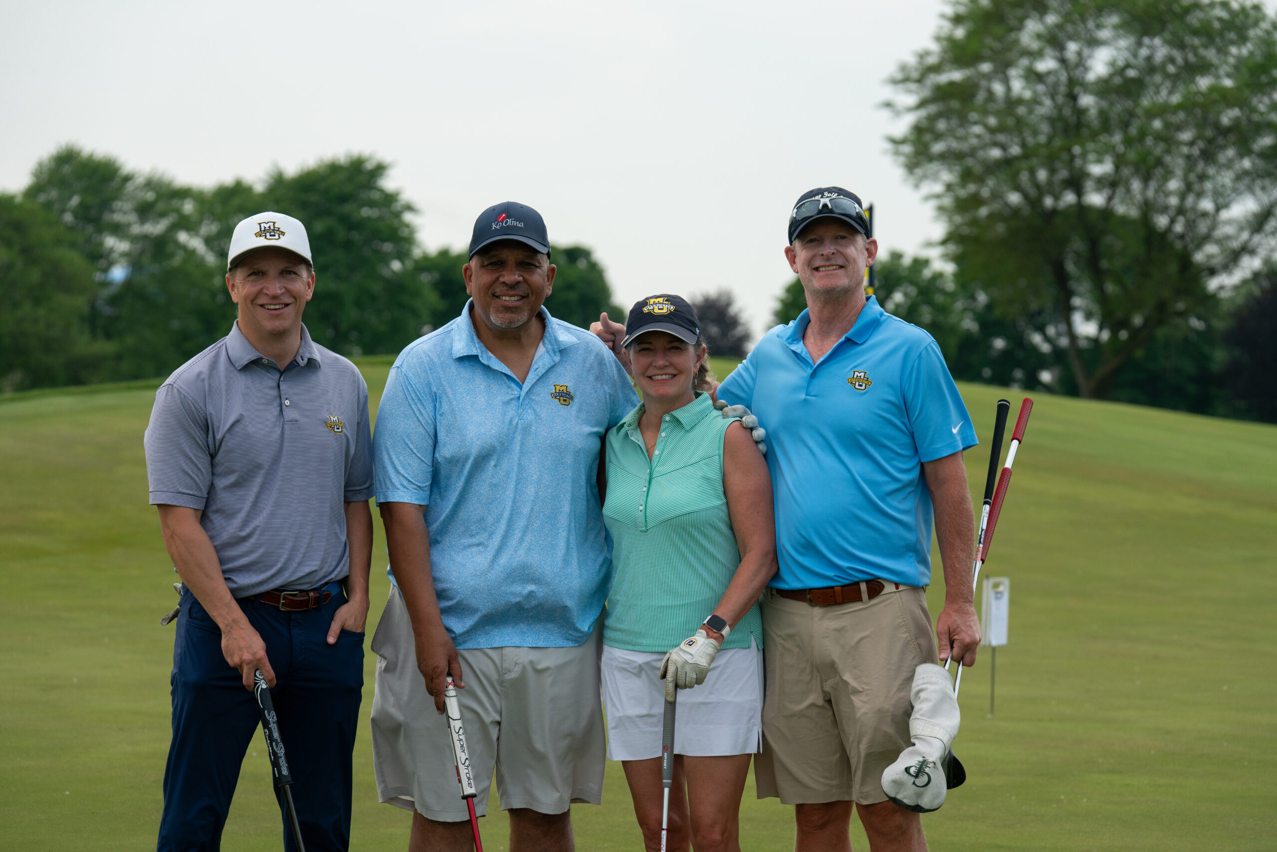 Four golfers posing on a green course