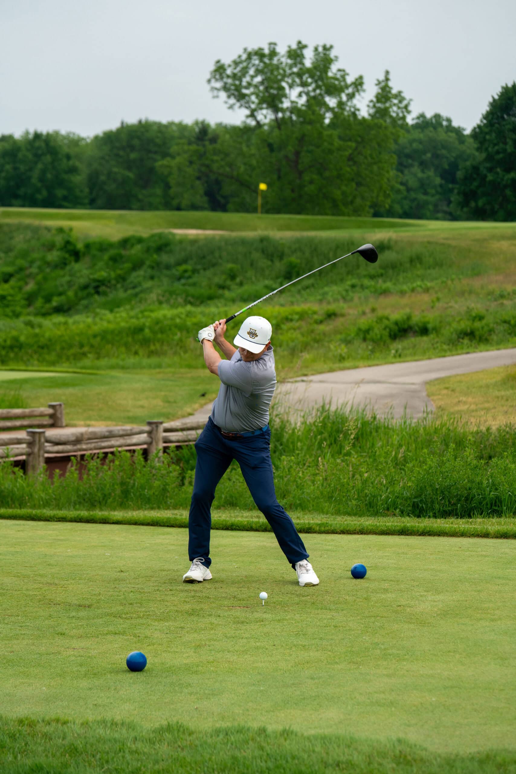Golfer swinging driver on lush green course