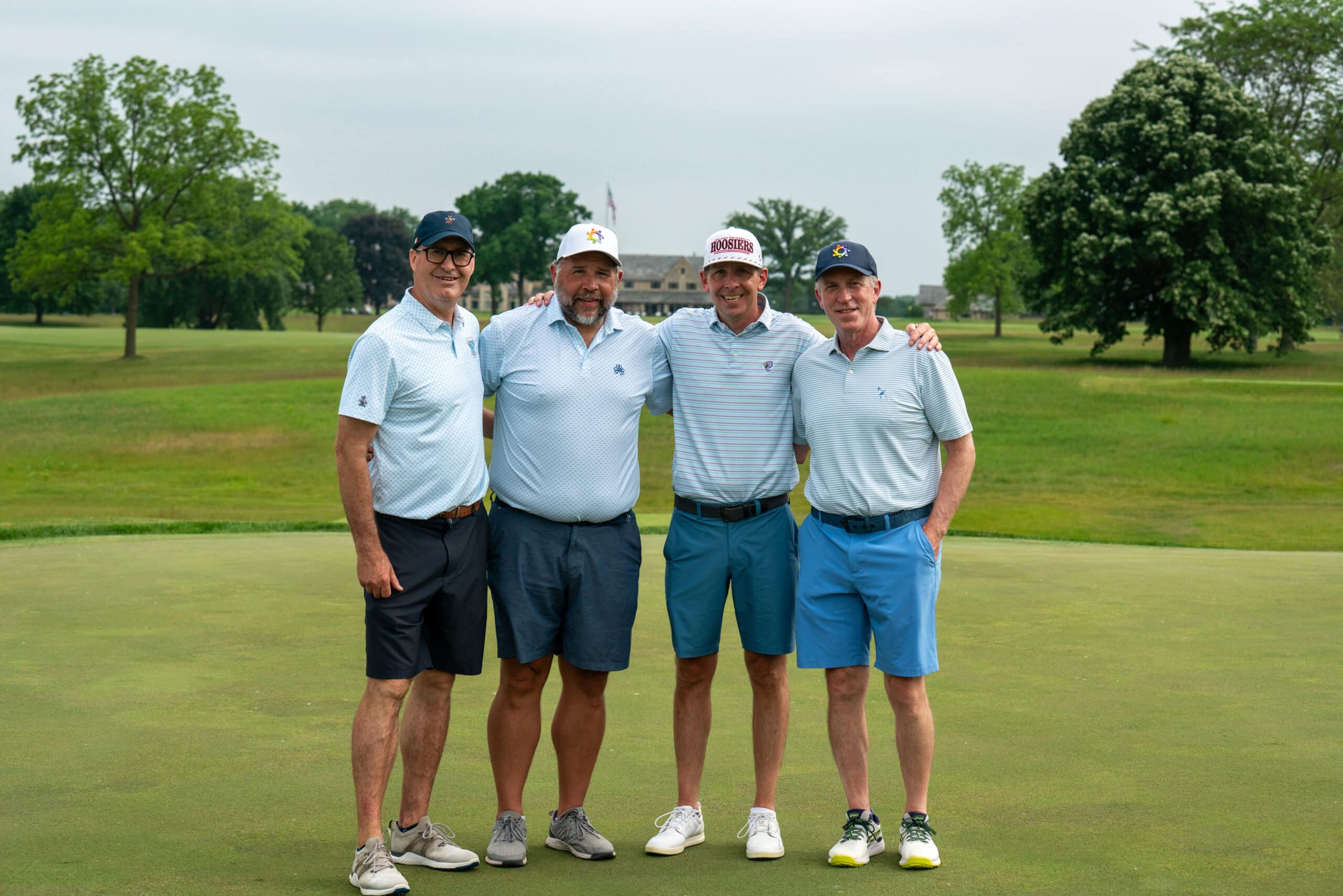 Four men posing on golf course green