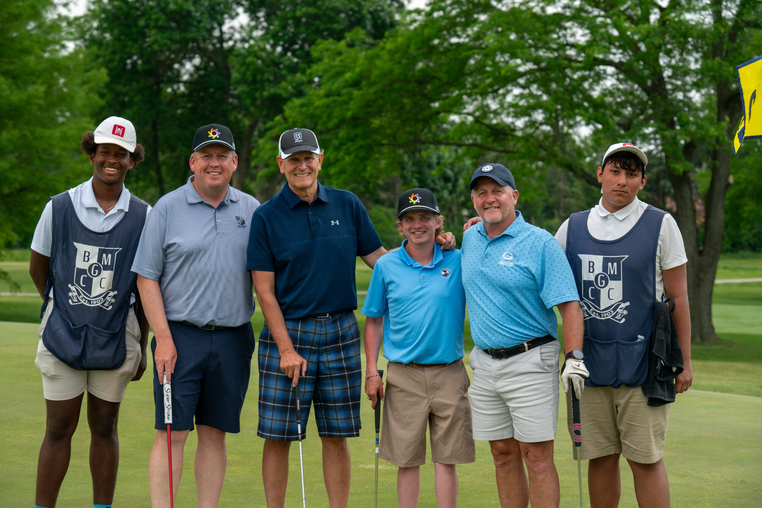 Six golfers posing together on a golf course
