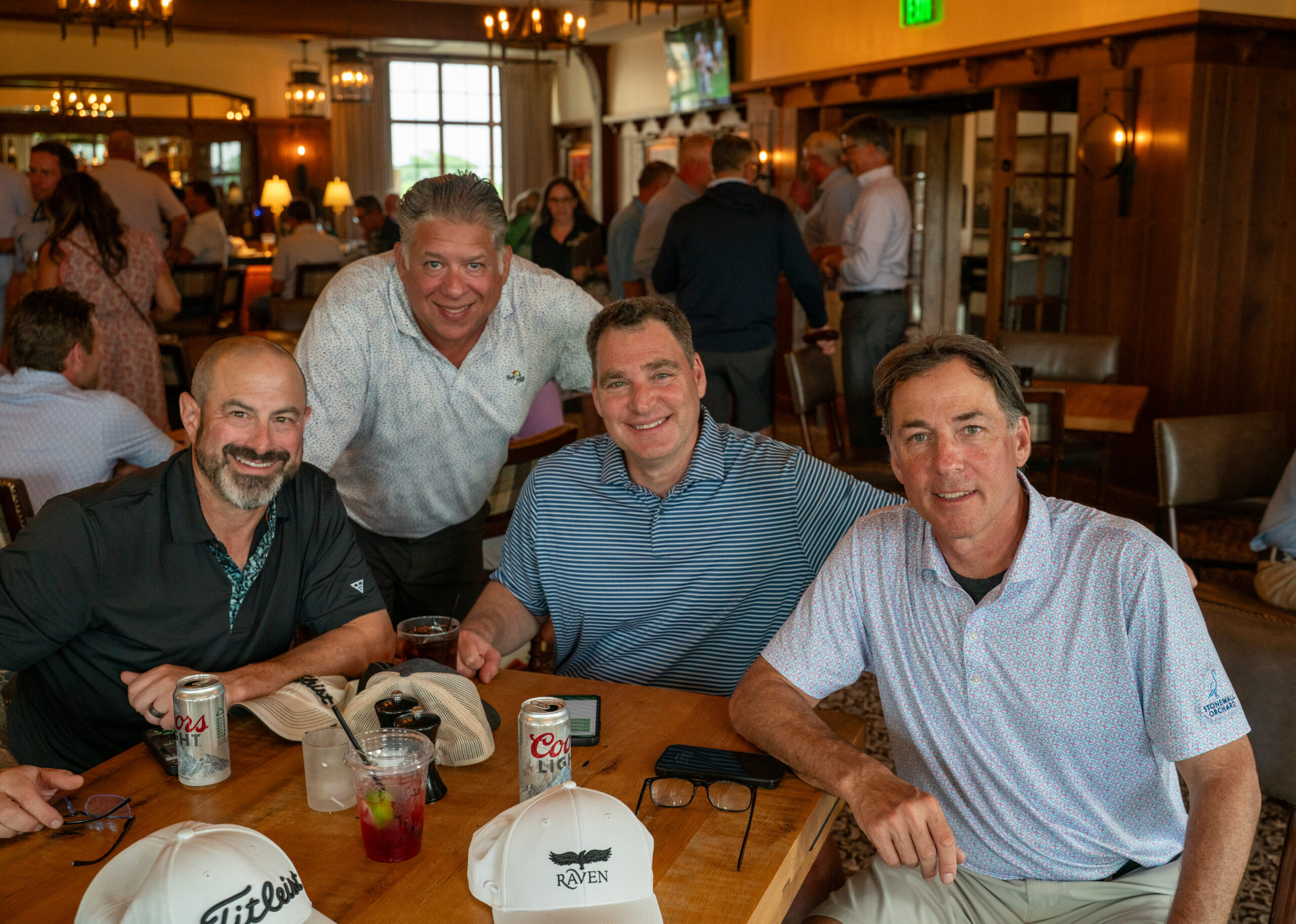 Four men smiling at restaurant table with drinks