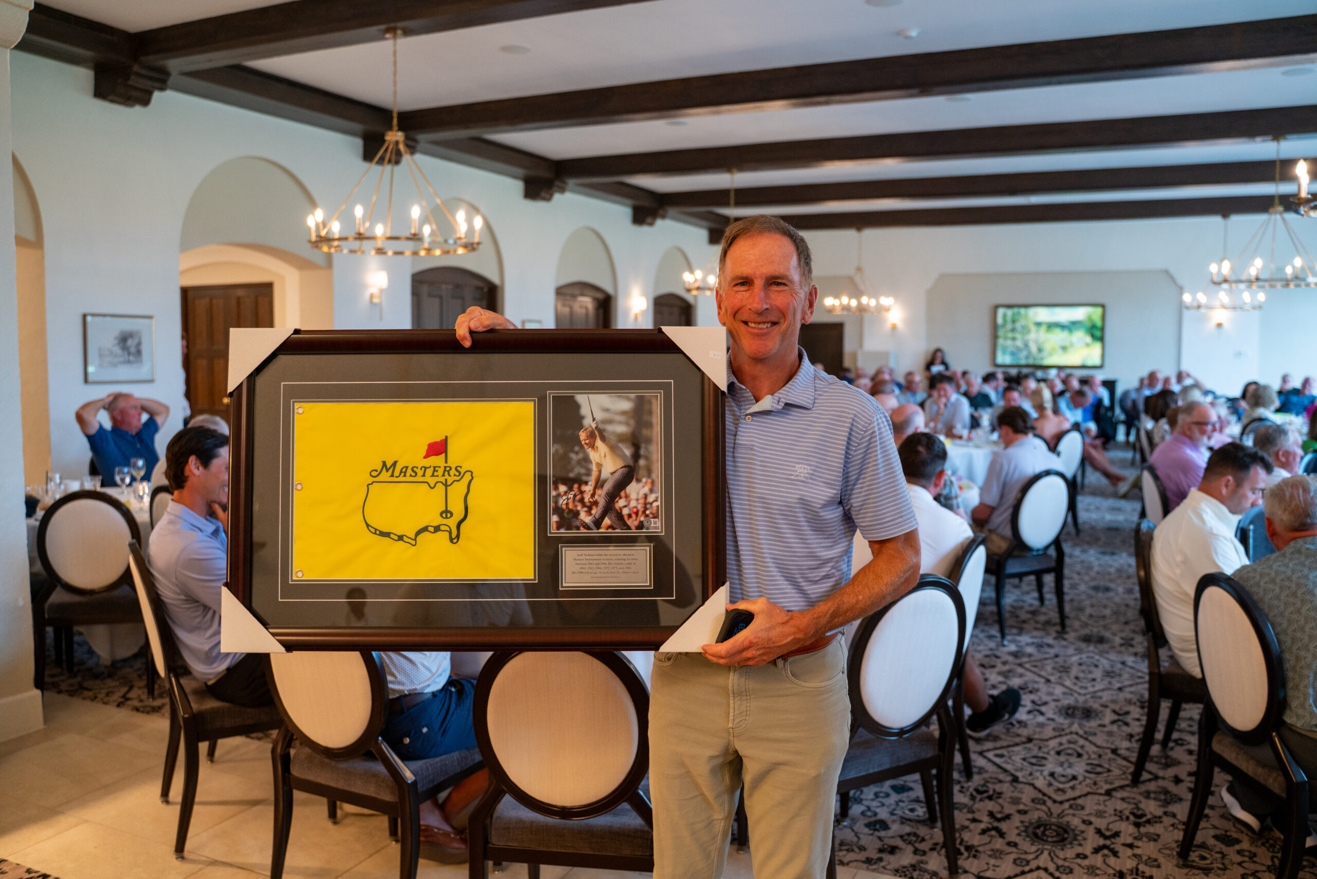 Man holding framed Masters golf memorabilia indoors