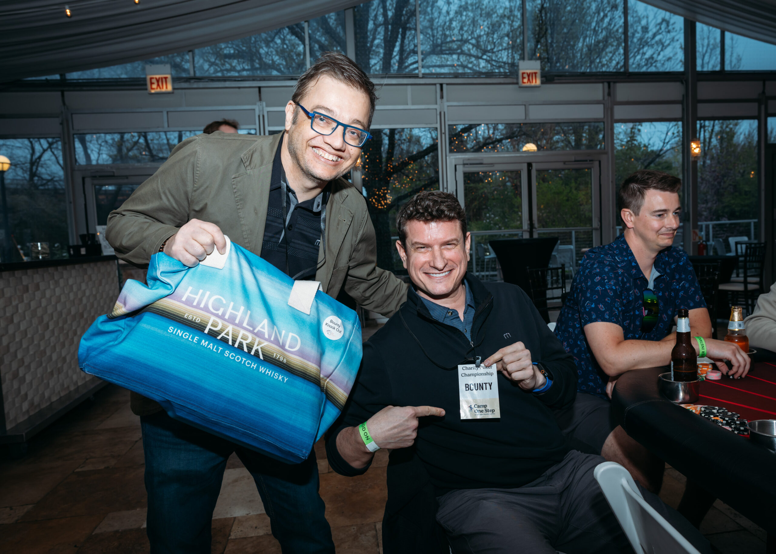 Two smiling men at event with drinks.