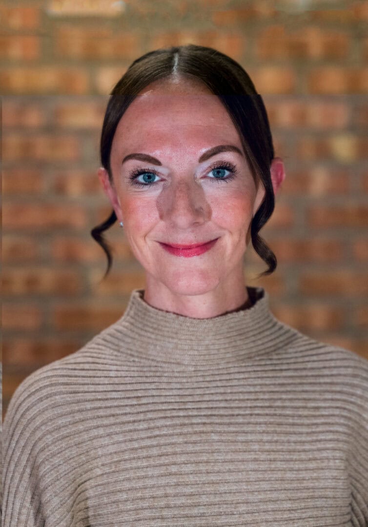 Close-up of smiling woman with blue eyes at Camp One Step featuring outdoor adventure setting.