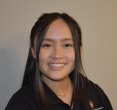 Supportive young woman at Camp One Step smiling outdoors, promoting childhood cancer support programs.