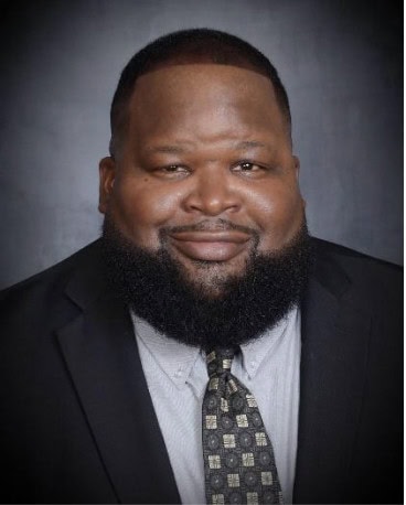 Warm African American man in professional attire, emphasizing leadership and community engagement at Camp One Step.