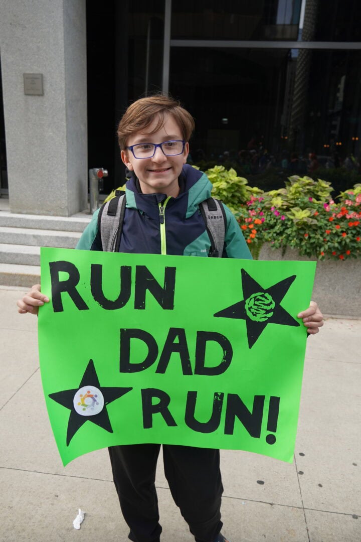 Child holding a sign for a charity run event at Camp One Step.