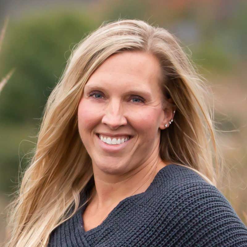 Young woman smiling outdoors at Camp One Step, fostering hope and community for children with cancer.