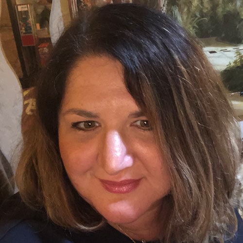 Relaxed woman at Camp One Step outdoor retreat, smiling outdoors in natural setting.