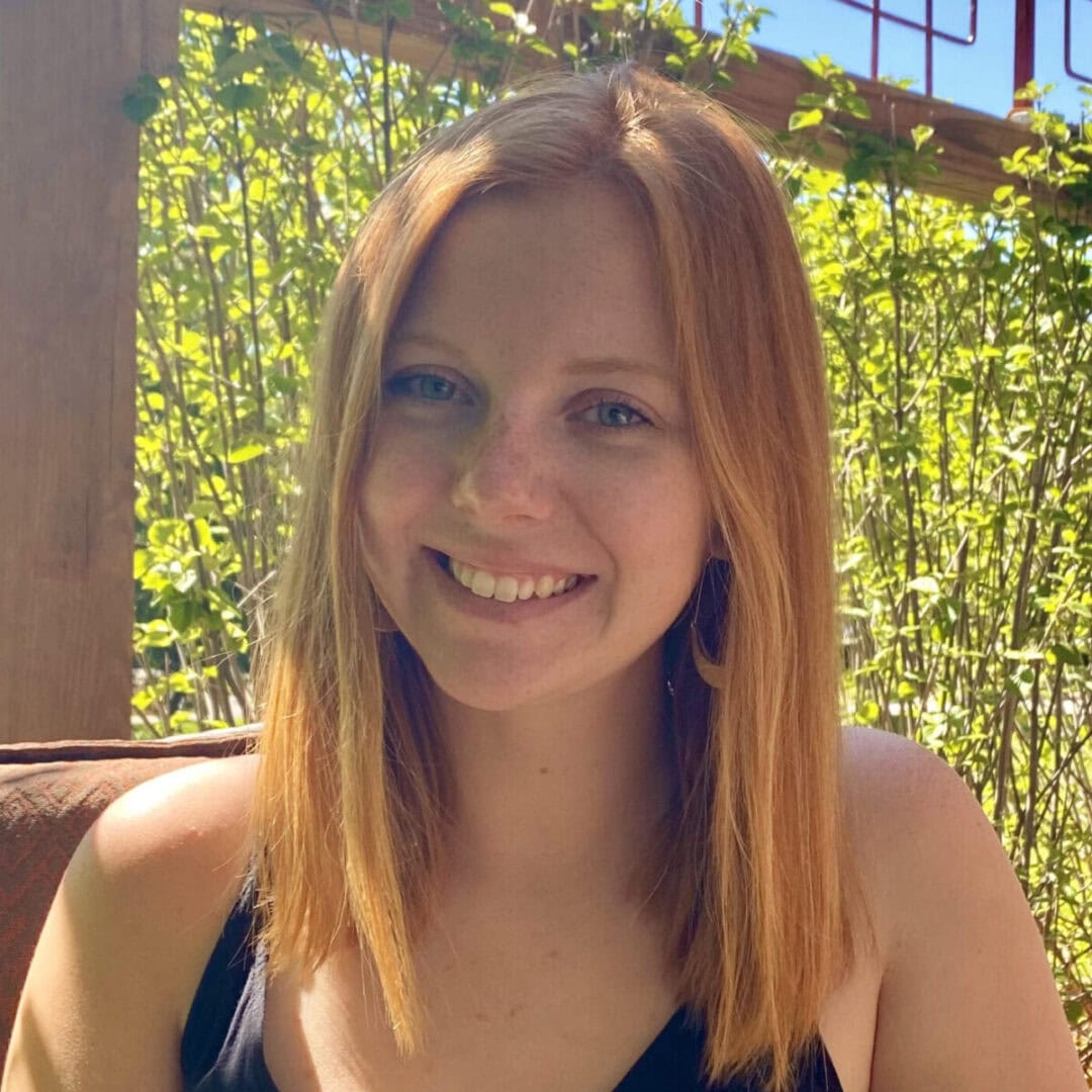 Warm smiley woman enjoying outdoor camp setting, lush green foliage background.