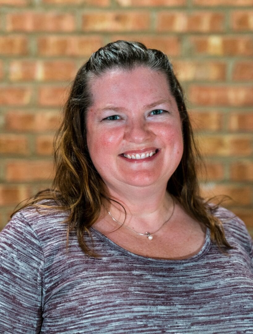 Smiling woman with a brick wall background at Camp One Step.