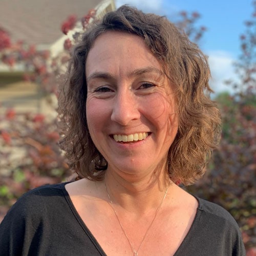 Empowered woman smiling outdoors at Camp One Step, supporting children's mental health and wellness.