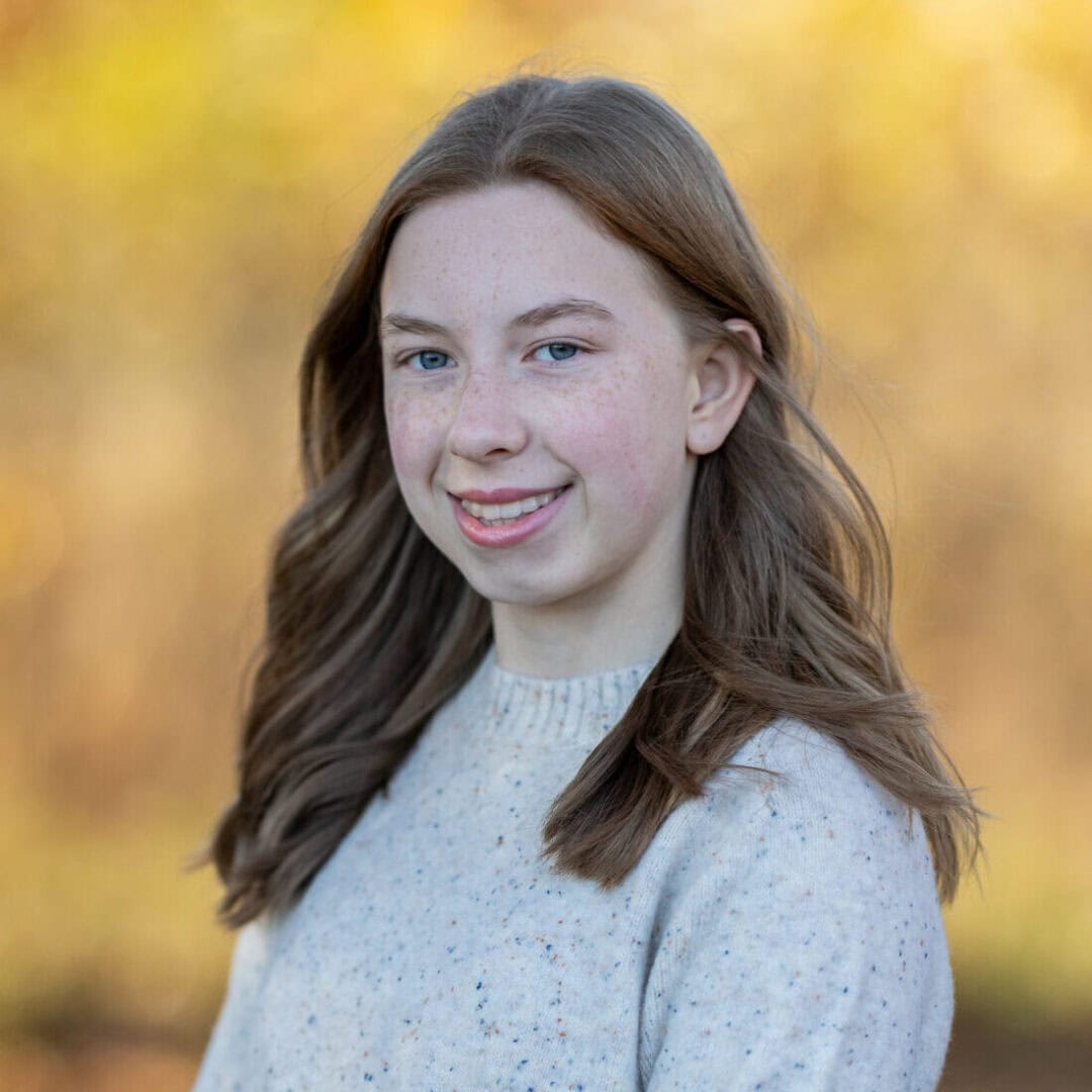 Bright young girl with blue eyes and red hair smiling outdoors during fall at Camp One Step.