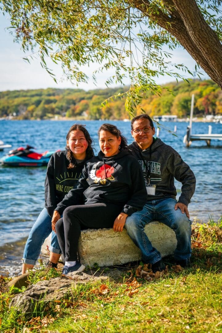 Family enjoying outdoor camping at Camp One Step by a lake with autumn foliage.