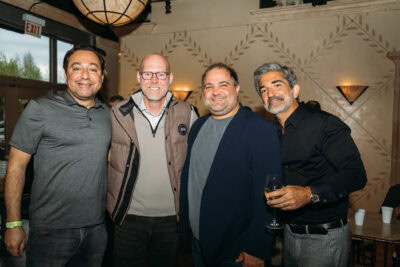 Diverse group of men at Camp One Step charity event celebrating fundraising efforts.