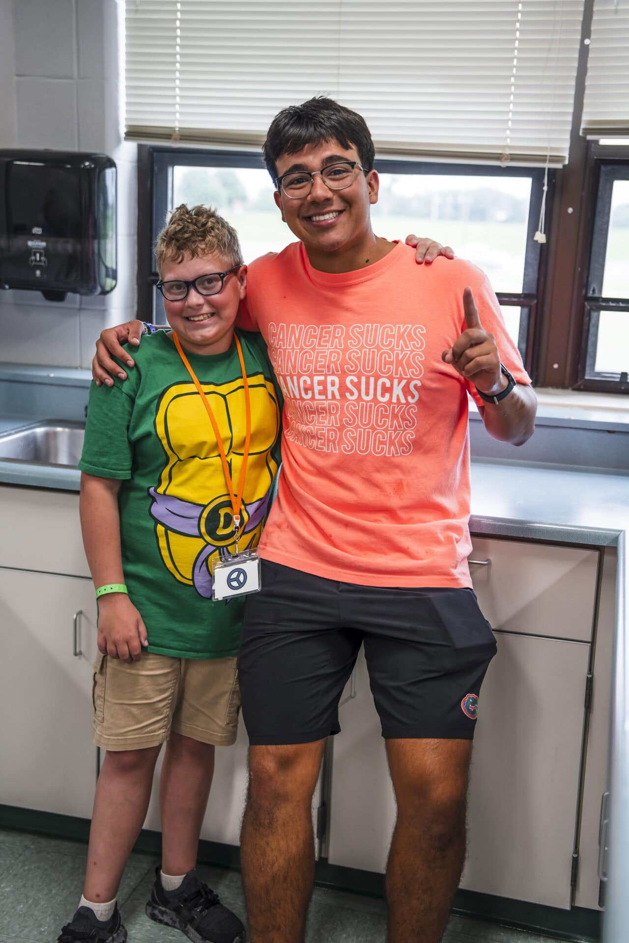 Smiling young camper and counselor indoors at Camp One Step, promoting inclusivity and support.