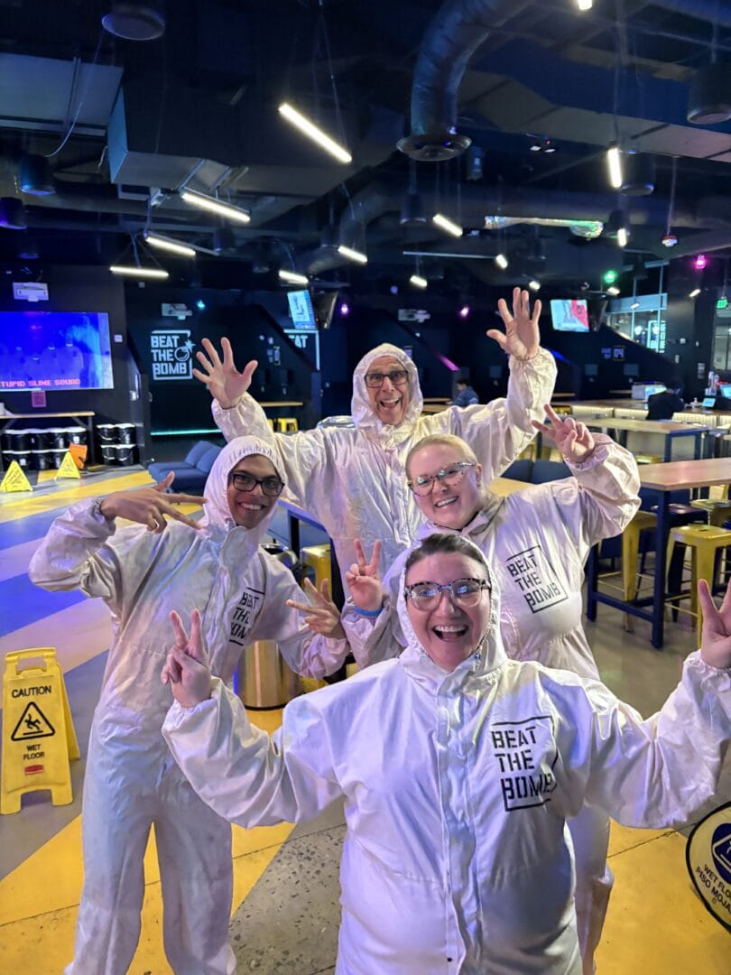 High-energy team members in white jumpsuits celebrating at Camp One Step indoor trampoline park.