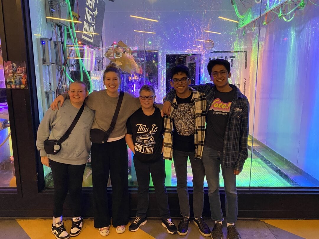 Colorful neon-lit indoor amusement park with happy friends celebrating at Camp One Step.