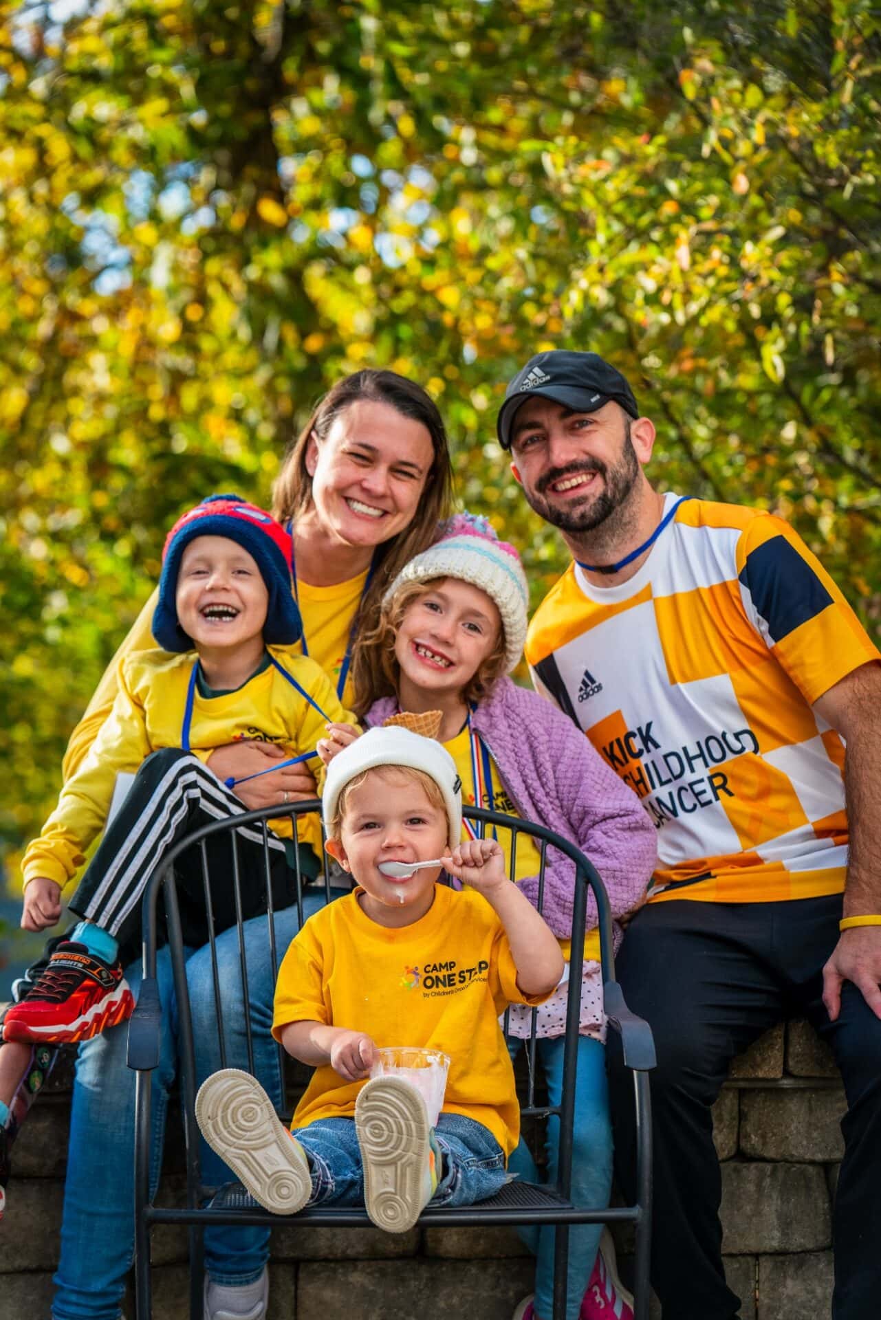 Happy family at Camp One Step, surrounded by autumn trees, celebrating childhood cancer support.