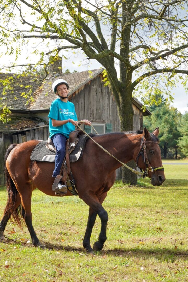 Child riding horse at Camp One Step outdoor camp.