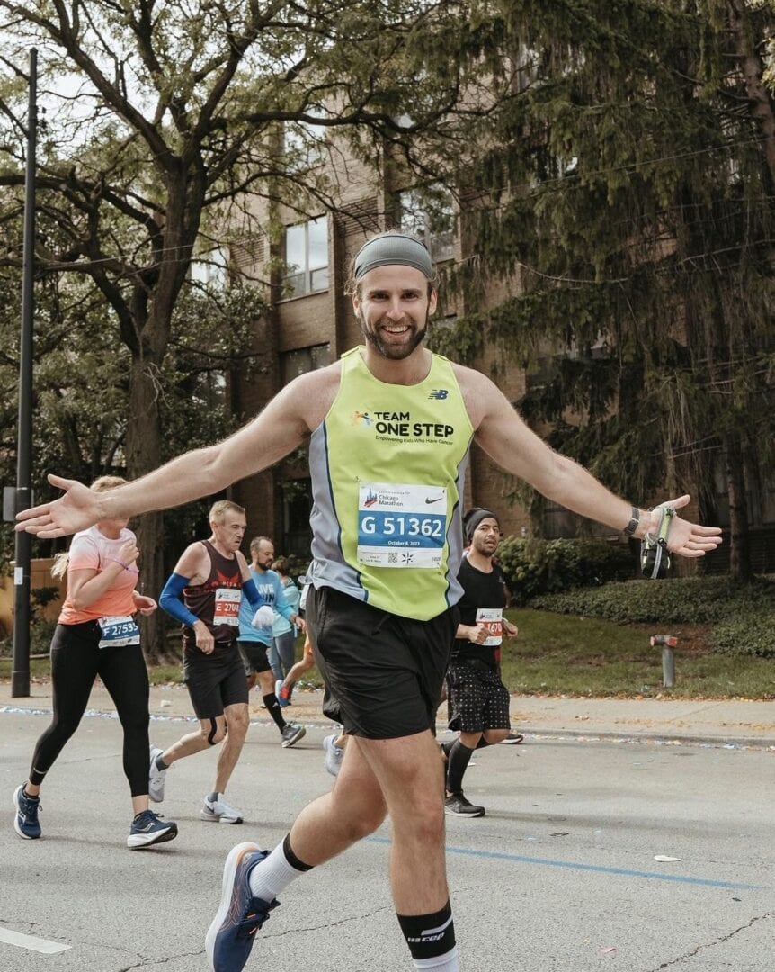 Active male runner smiling with arms wide open during the race.