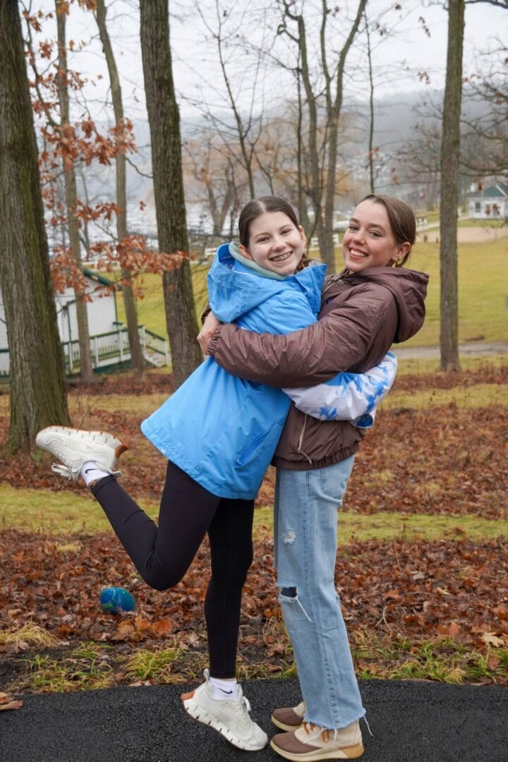 Joyful girls hugging outdoors at Camp One Step in autumn.
