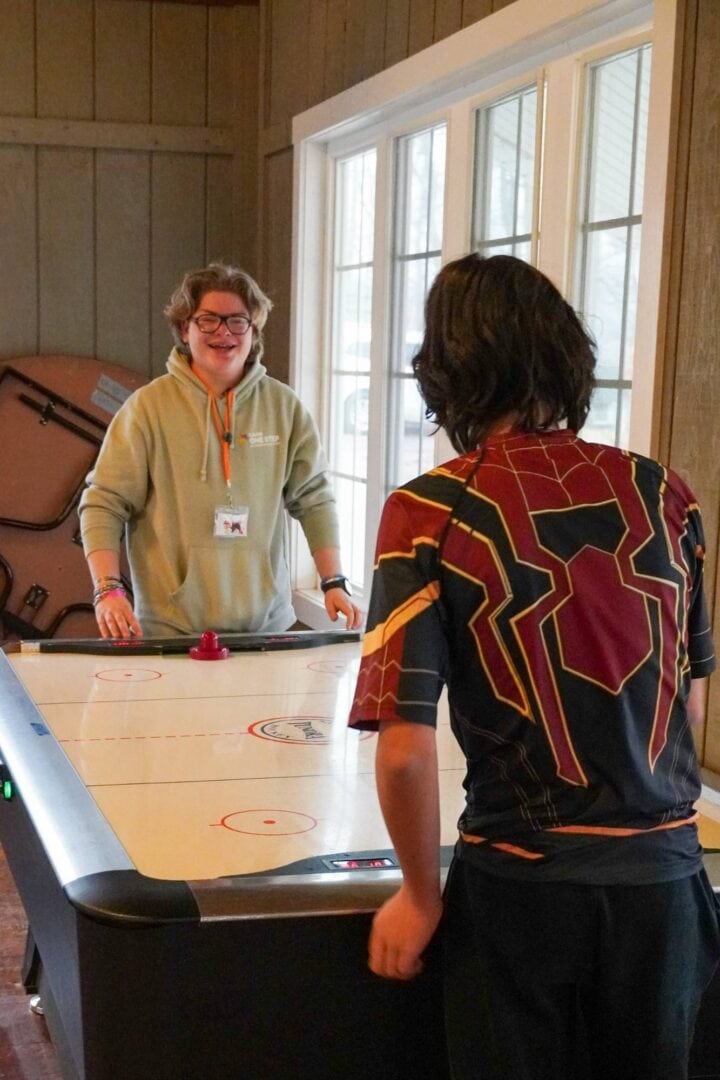 Friendly staff playing air hockey at Camp One Step retreat center for kids with cancer.