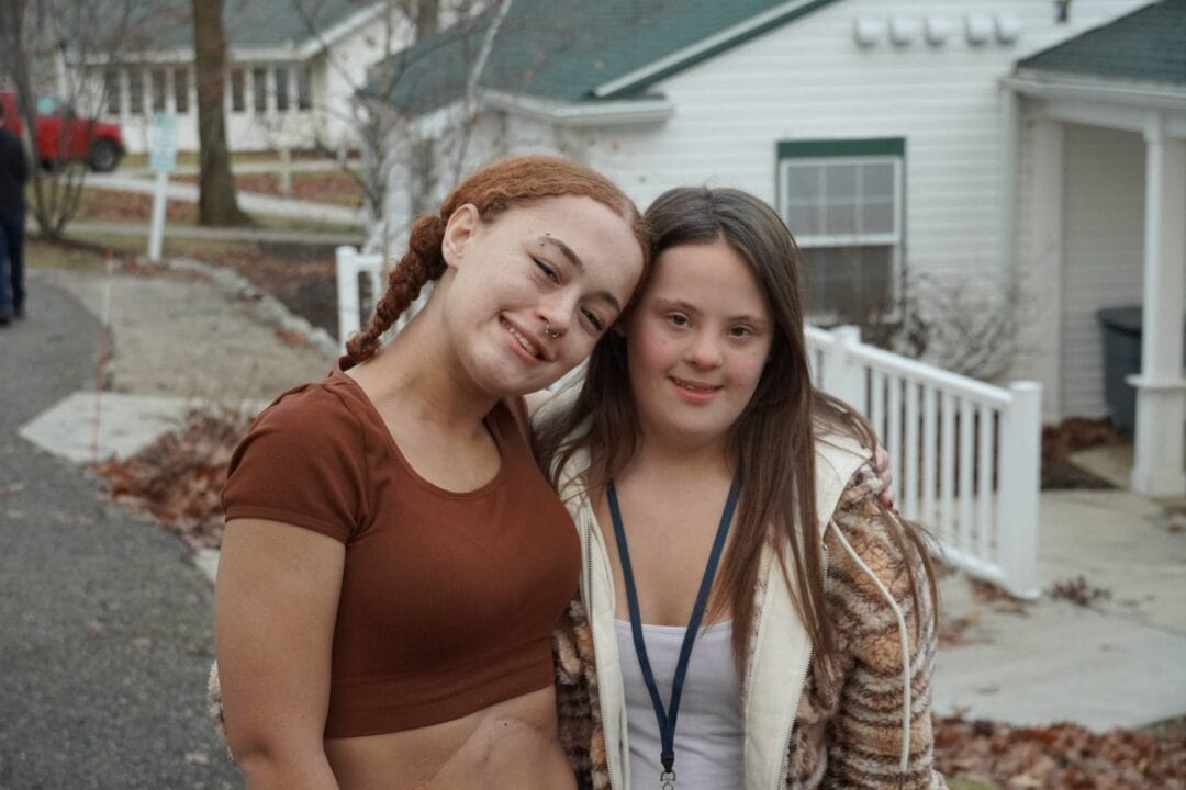 Relaxed young women enjoying outdoor Camp One Step program, embracing friendship in community.