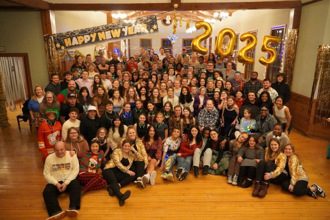 Joyful group celebrating New Year's Eve at Camp One Step 2025 with festive decorations and happy faces.