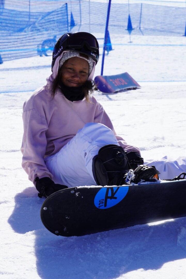 1. Young girl in snow gear sitting on a snowboard at Camp One Step ski resort.