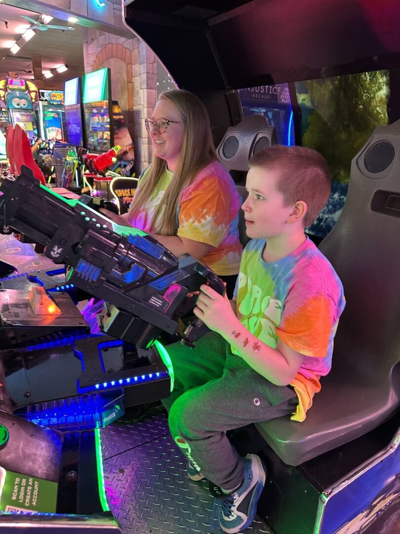 Colorful arcade game room with kids playing on futuristic gaming machines.