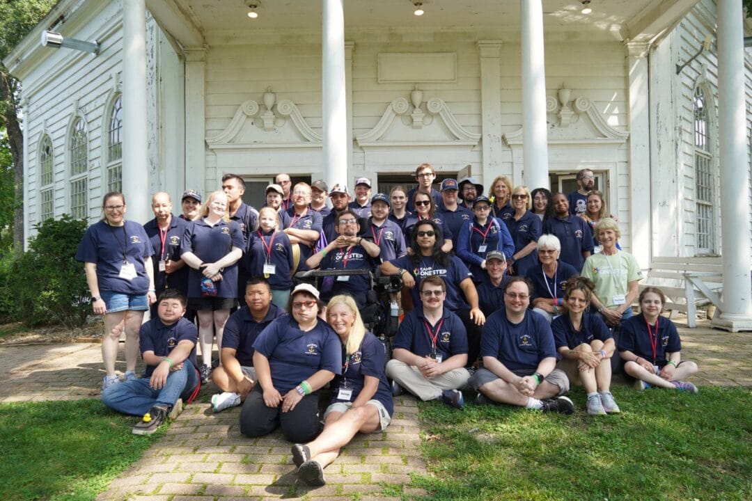 Diverse group of volunteers and staff at Camp One Step in front of an old white church.