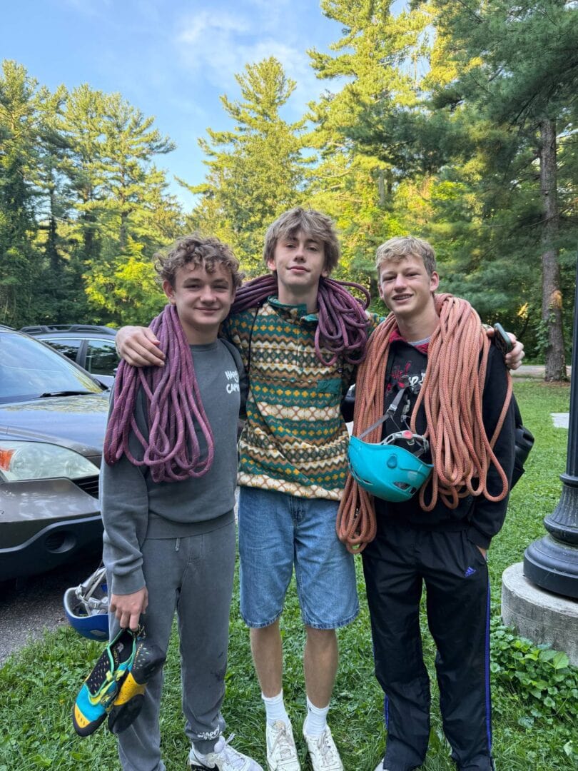 Adventurous young climbers with ropes and helmets at Camp One Step, surrounded by lush trees and nature.