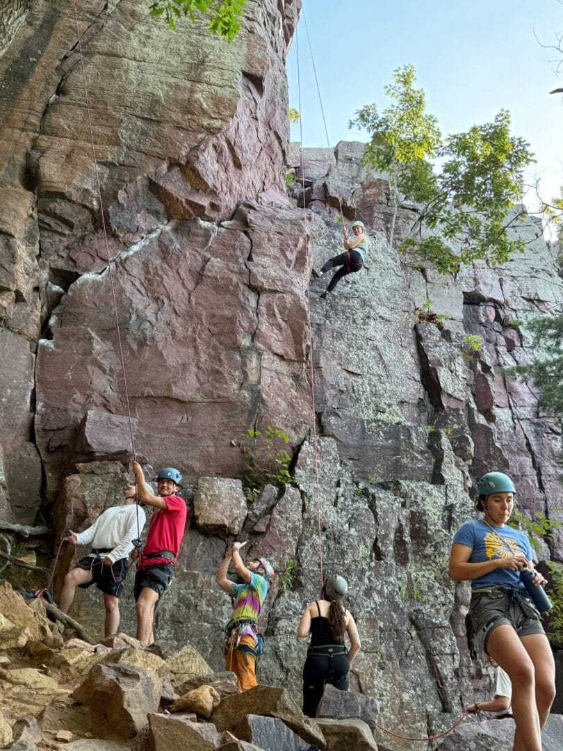 Climbers enjoying outdoor rock climbing at Camp One Step, surrounded by nature and scenic rocky cliffs.