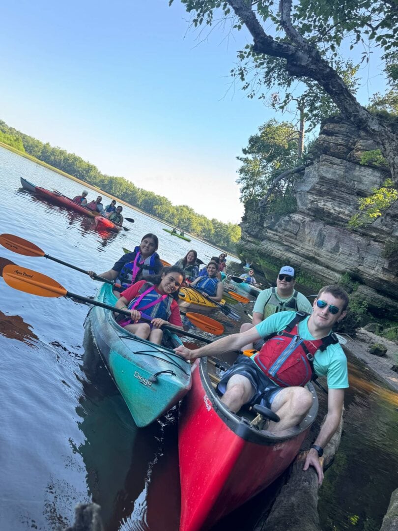 Kayaking at Camp One Step along the peaceful river surrounded by lush greenery and rocky cliffs.