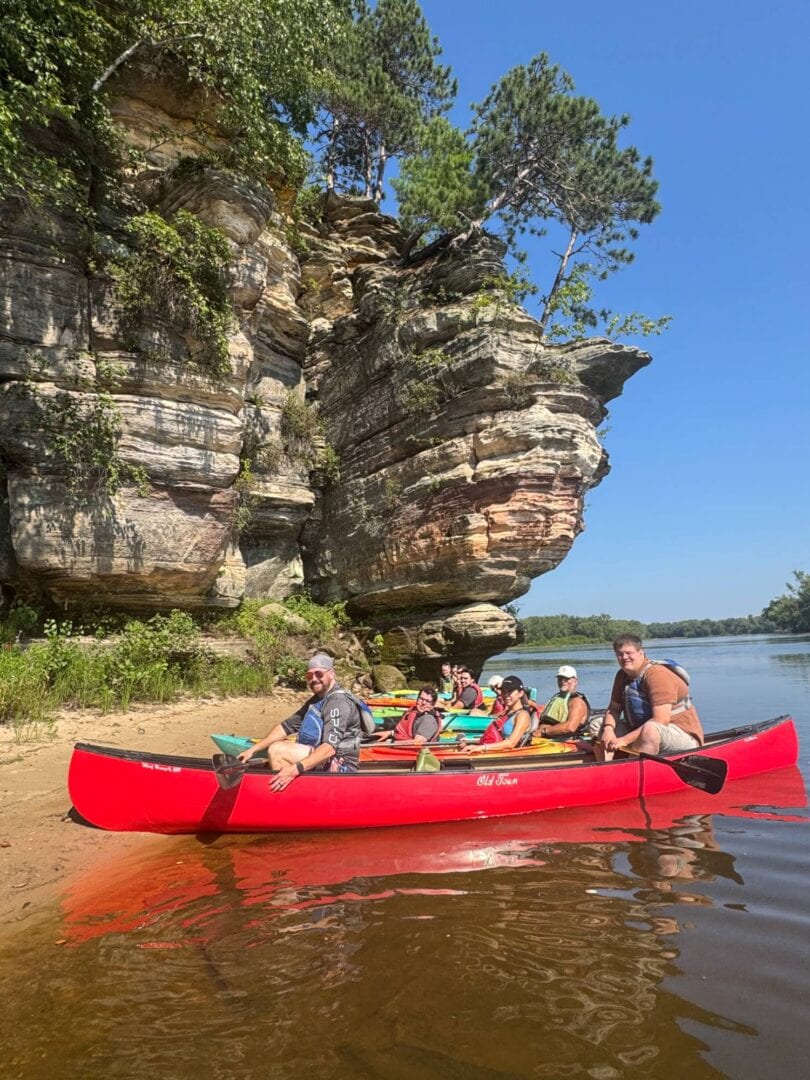People kayaking by scenic canyon and river landscape.