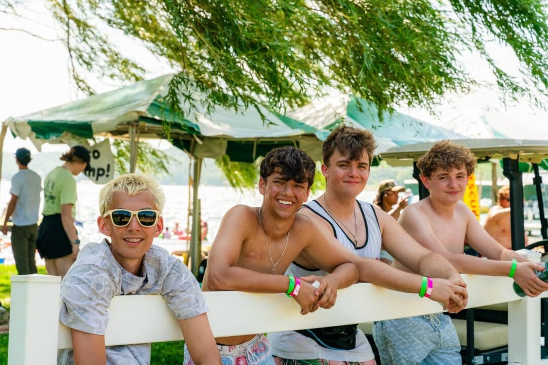 Young boys smiling and relaxing outdoors at Camp One Step near the lake.