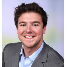 Bright smiling young man in professional attire at Camp One Step event.