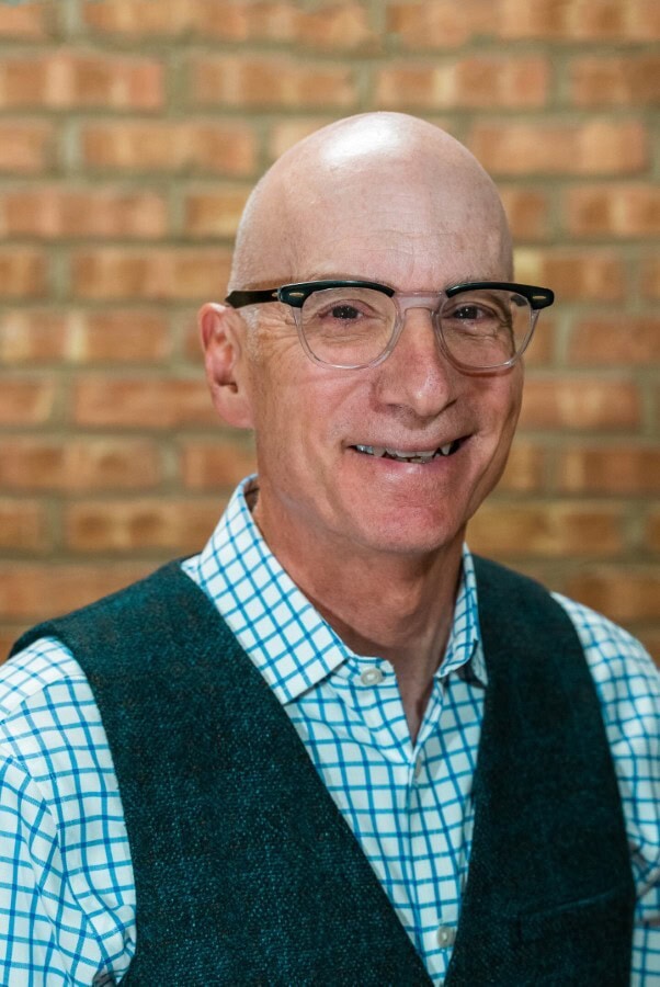 Elderly man with glasses smiling at Camp One Step, inspiring leadership and hope.